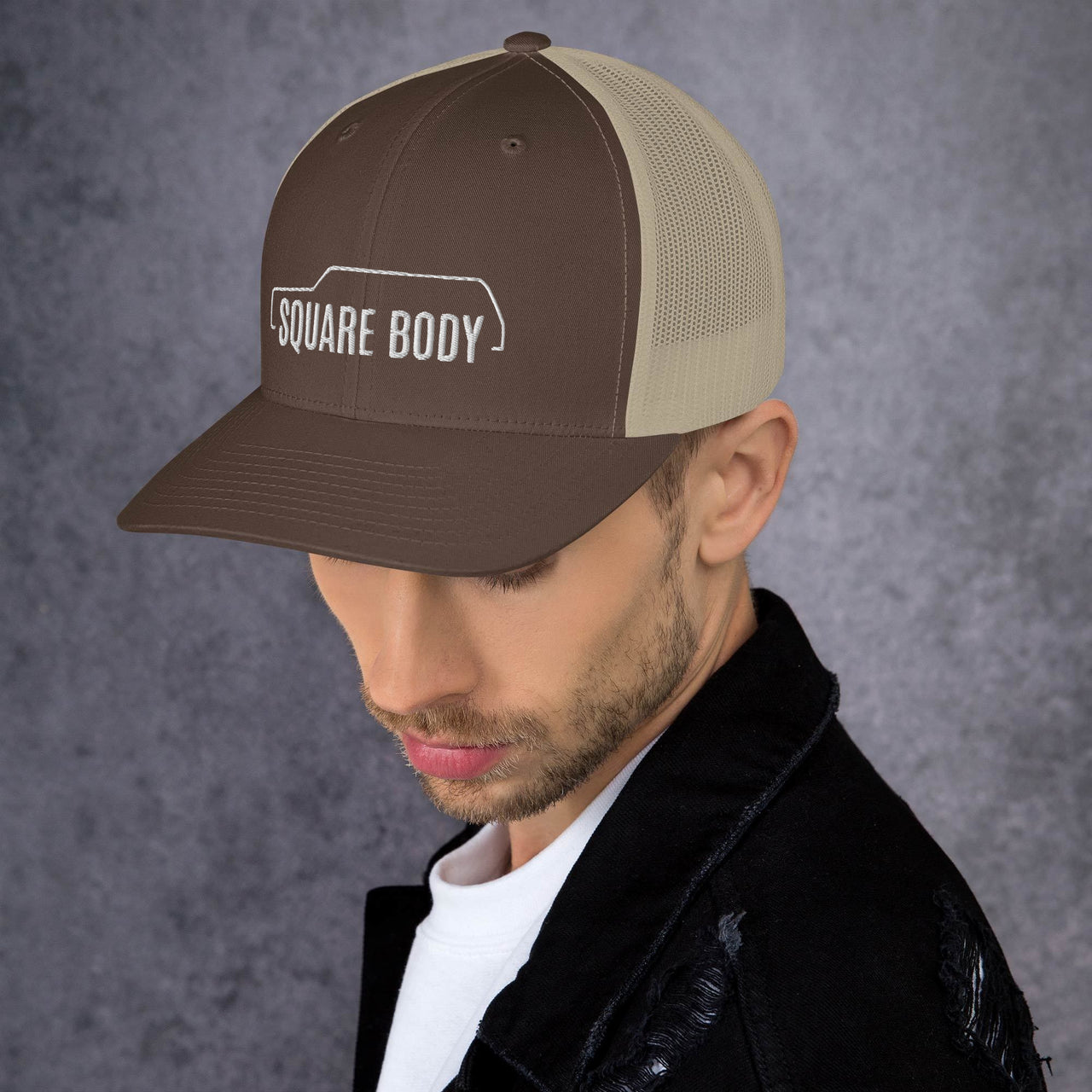 man wearing a 3/4 view of a square body suburban trucker hat from aggressive thread in brown