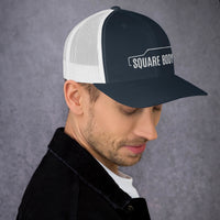 Thumbnail for man wearing a 3/4 view of a square body suburban trucker hat from aggressive thread in navy and white